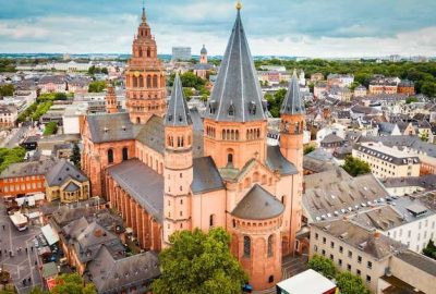 Das Bild zeigt eine Grosstadt mit vielen Gebauden, darunter auch den Mainzer Dom. Es zeichnet sich durch mittelalterliche Architektur, eine Mischung verschiedener Gebaude und eine Kirche als herausragendes Bauwerk aus.