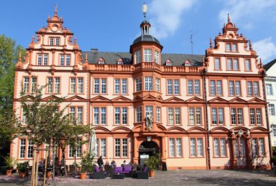 Schauplatz ist Mainz. Das Bild zeigt ein groses Gebaude mit vielen Fenstern, im Hintergrund das Gutenberg-Museum.