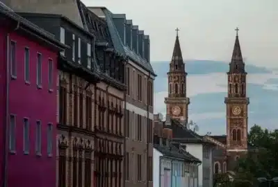 Bei dem Bild handelt es sich um ein Foto eines Uhrturms in der Stadt Ludwigshafen am Rhein. Es verfügt über einen mittelalterlichen Architekturturm mit Kirchturm und Uhr vor einer Kulisse aus Gebäuden und dem Himmel. Die Szene fängt eine Mischung aus historischen und urbanen Elementen ein.