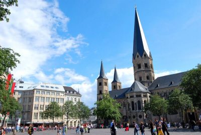 Das Foto zeigt ein großes Gebäude mit einem hohen Turm in Bonn, Deutschland. Es weist mittelalterliche Architektur auf und ist wahrscheinlich eine Kirche oder ein Gotteshaus.