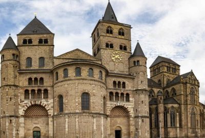 Das Bild zeigt den Trierer Dom in Deutschland, ein großes Steingebäude, das sich durch seine mittelalterliche Architektur auszeichnet.