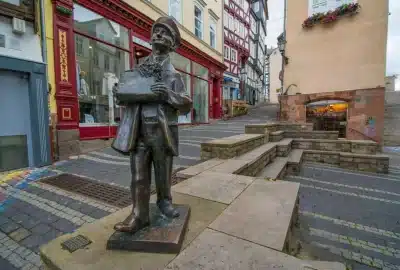 Das Bild zeigt eine Bronzestatue von Paul Wedepohl Christian in Marburg. Die Skulptur steht im Freien, auf dem Boden in der Nähe einer Straße in der Stadt. Das Kunstwerk spiegelt Elemente von historischer und künstlerischer Bedeutung wider und trägt zum Stadtbild bei.