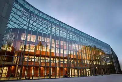 Das Bild zeigt ein Geschäftsgebäude, dessen Glaswände für viel Licht und Reflexionen sorgen. Es befindet sich in einem urbanen Umfeld, der zeitgenössischen Architektur der Philipps-Universität Marburg in Deutschland.