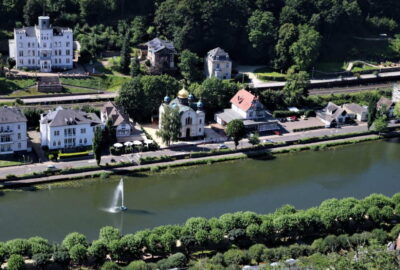 Das Foto zeigt einen ruhigen Wasserlauf mit einem zentral gelegenen Brunnen. Die Szenerie ist Teil von Bad Ems, einer charmanten Stadt in Deutschland, die für ihre natürliche Schönheit und ruhige Atmosphäre bekannt ist.