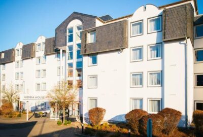 Das Bild zeigt ein weißes Gebäude mit zahlreichen Fenstern, das als Vienna House identifiziert wurde. Dieser Hotelstandort kann mit dem Hotel Limburg in Deutschland in Verbindung gebracht werden.