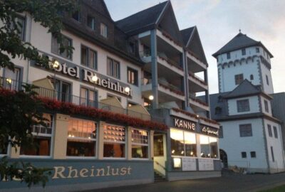 Das Bild zeigt das Hotel Rheinlust, ein Gebäude, das sich durch seine zahlreichen Fenster auszeichnet. Es befindet sich in Deutschland und zeugt von architektonischer Eleganz inmitten einer pulsierenden Stadtkulisse.