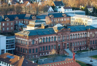 Blick von oben auf die Stadt Kaiserslautern, in der sich viele Gebäude befinden, unter denen das Museum hervorsticht