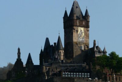 Das Bild zeigt die Pfalz Cochem in Deutschland, eine beeindruckende Burg mit einer Flagge auf dem Turm.