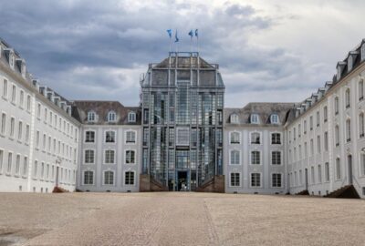 Das Bild zeigt das Saarbrücker Schloss, ein großes Gebäude, das sich durch seine vielen Fenster und seine beeindruckende Fassade auszeichnet.