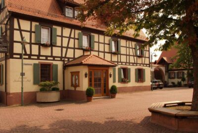 Das Bild zeigt ein Hotel an einer Backsteinstraße mit Außenbereich.