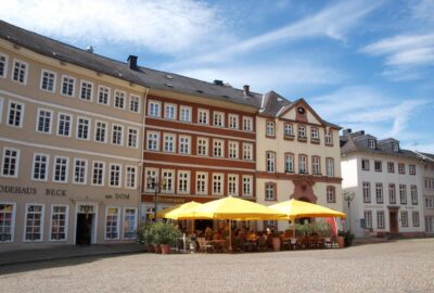 Das Bild zeigt ein Restaurant im Dom Ristorante am Domplatz in Wetzlar, Limburg, Deutschland. Es verfügt über einen Außenbereich mit zahlreichen Tischen und Sonnenschirmen, sodass die Gäste ihre Mahlzeiten im Freien genießen können.